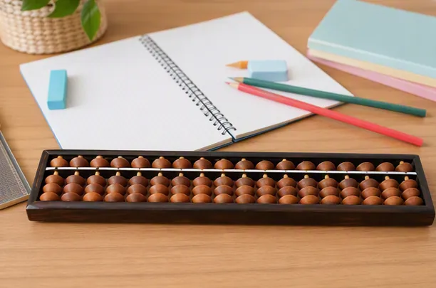 Wooden soroban in front of an open squared notebook, pencils and an eraser on a desk